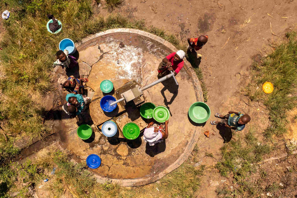 A group of individuals congregated around a well in the village of Quionga, Mozambique. © iStock
