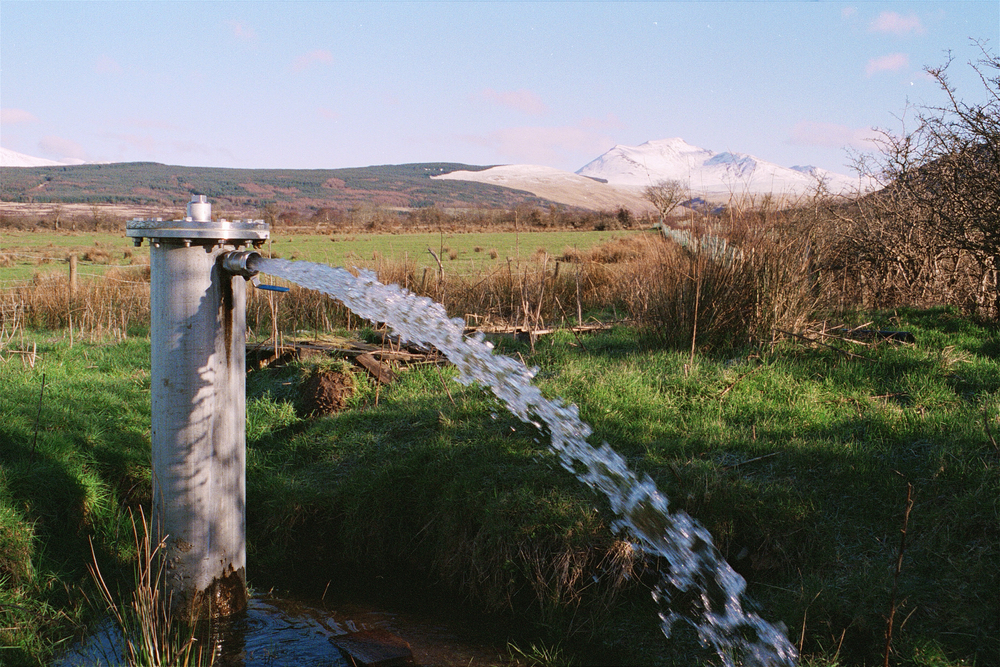 Water spurts out of a vertical metal tube.