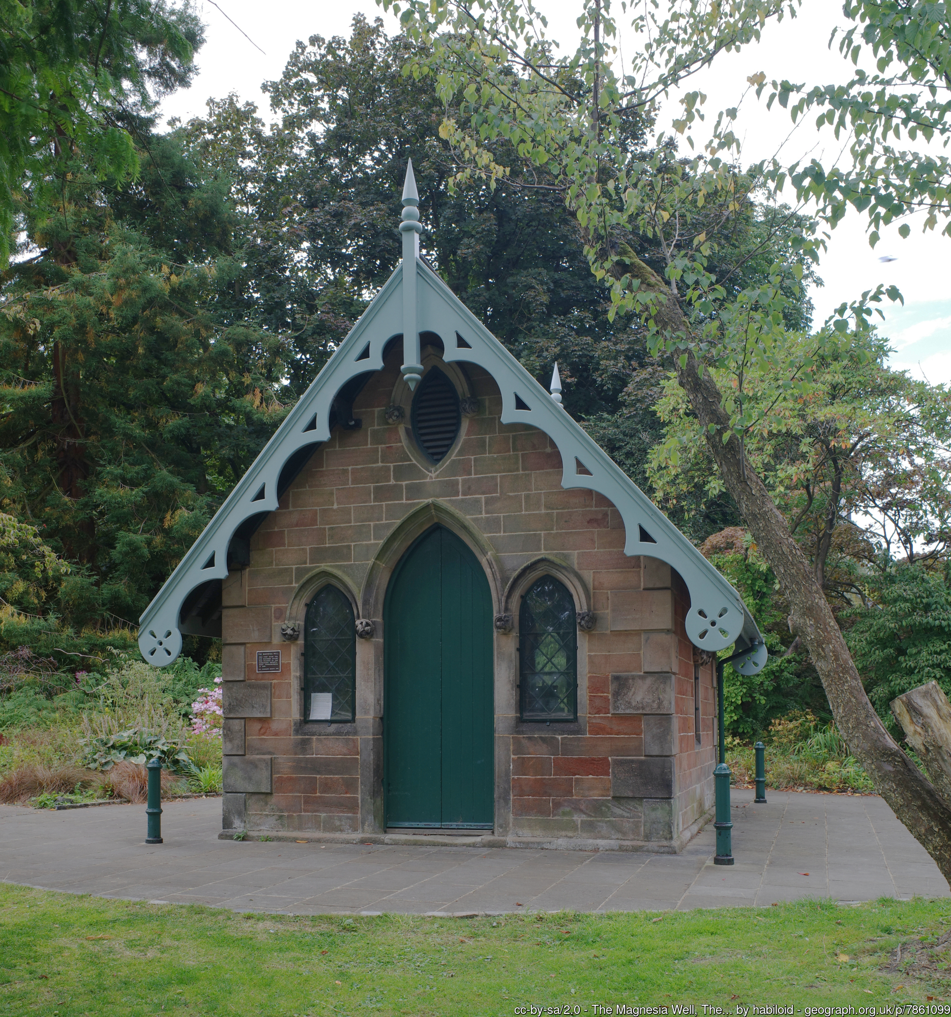 a small stone building with a pointed roof and an arched doorway with a green door