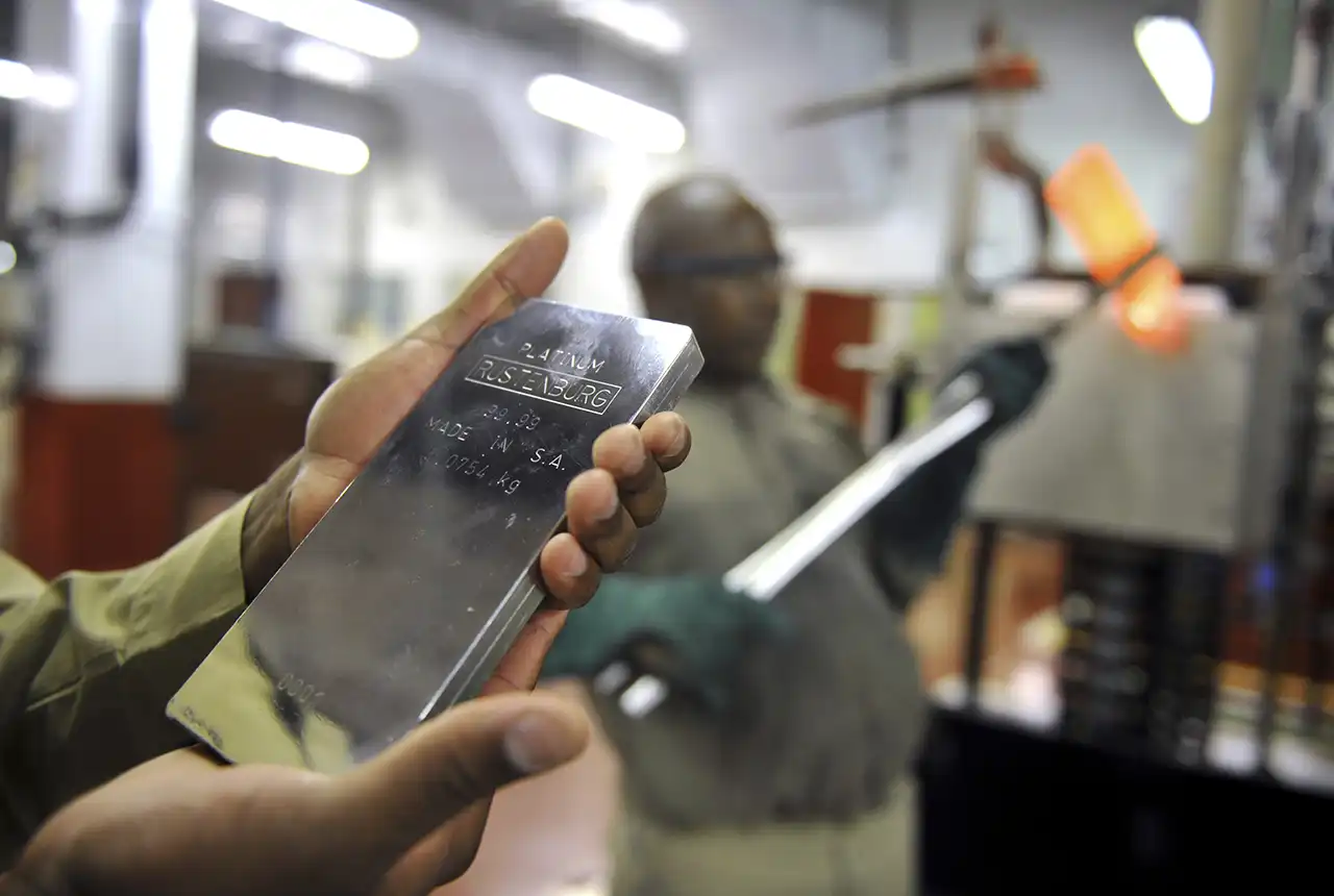 Precious Metals Refinery - PMR - A 5kg 99.99% pure Platinum ingot in the forge area of the Precious Metals Refinery in Rustenburg. A new red hot ingot is being removed from the furnace in the background - 14 October 2010. © Anglo American / VisualMedia.