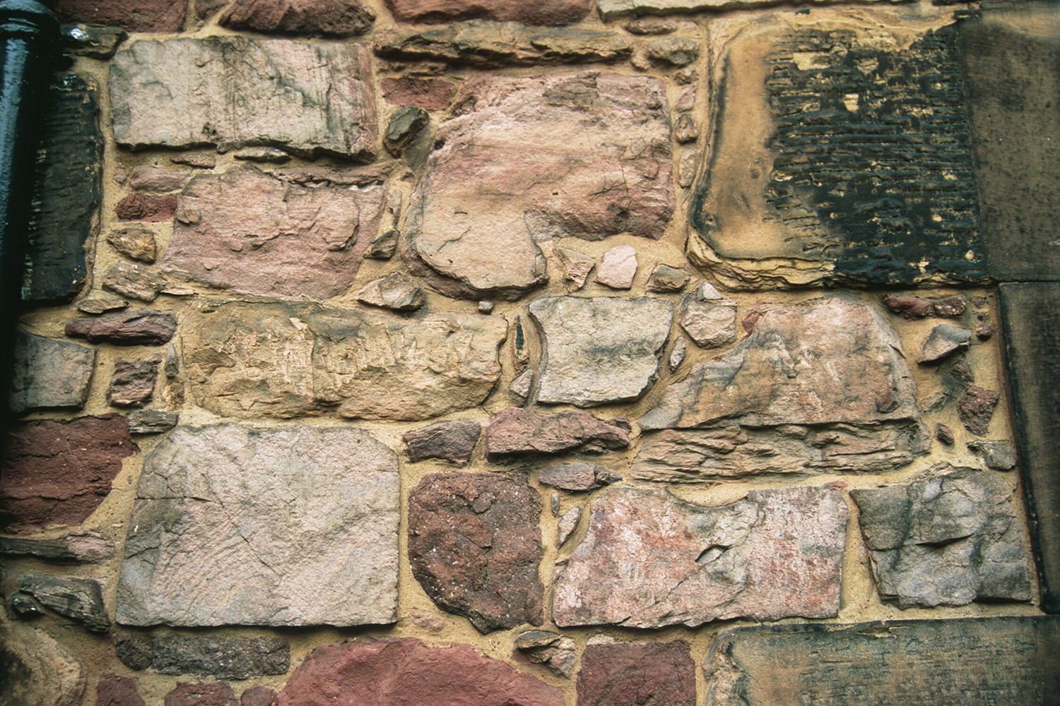 Different coloured sizes and shapes of building stones in a wall