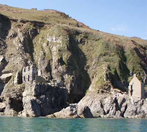 Remains of the village of Hallsands on the discontinuous mica schist platform. Towering above the village are coastal cliffs formed in Start Mica Schist and capped by head deposits. At high tide the waves break against the base of the rock platform.