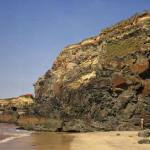 Nearby geology at Gwithian Towans; folding in Mylor Slates. An anticline with a near-horizontal hinge in silty banded slates. The cliff is capped by head overlain by blown sand.