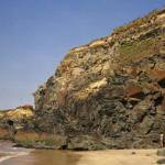 Nearby geology at Gwithian Towans; folding in Mylor Slates. An anticline with a near-horizontal hinge in silty banded slates. The cliff is capped by head overlain by blown sand.