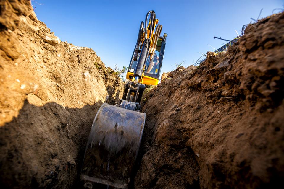 Mini Excavator. Excavator digs the foundation for the house. Photo credit Avalon_Studio.