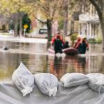 Flood Protection Sandbags with flooded homes in the background. Photo credit Marc Bruxelle.