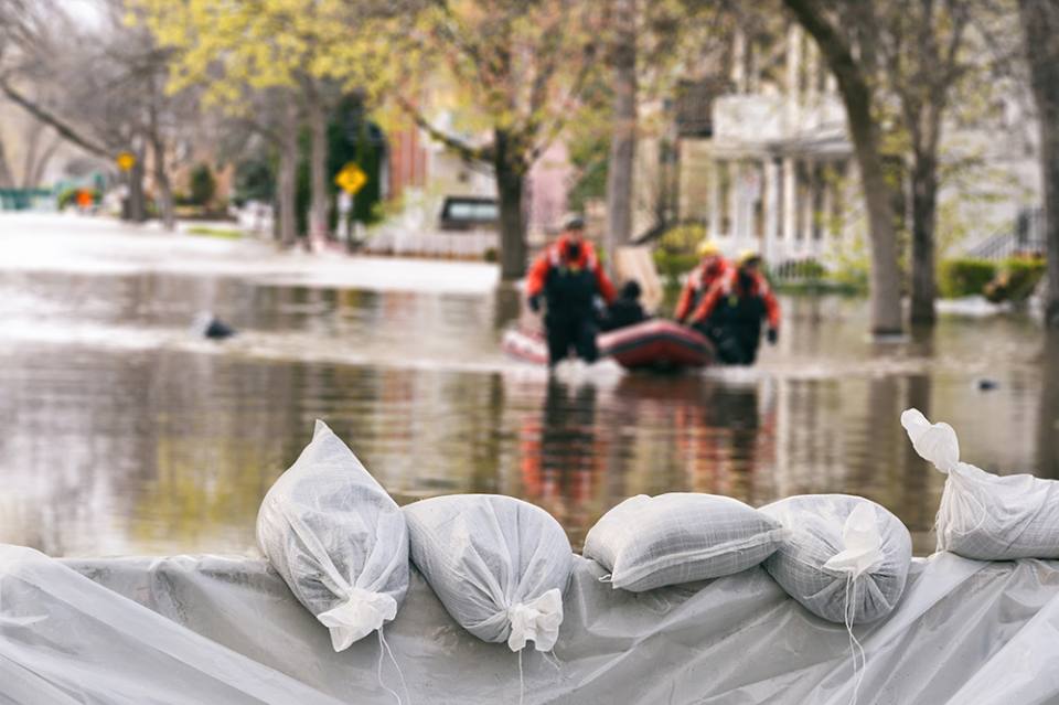 Flood Protection Sandbags with flooded homes in the background. Photo credit Marc Bruxelle.