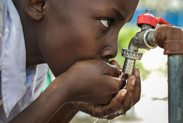 Young boy drinking water from tap, Tanzania. Photo by Chaucharanje, Pexels