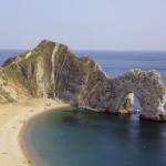 Durdle Door: an arch of rock protruding into the sea by a sandy beach