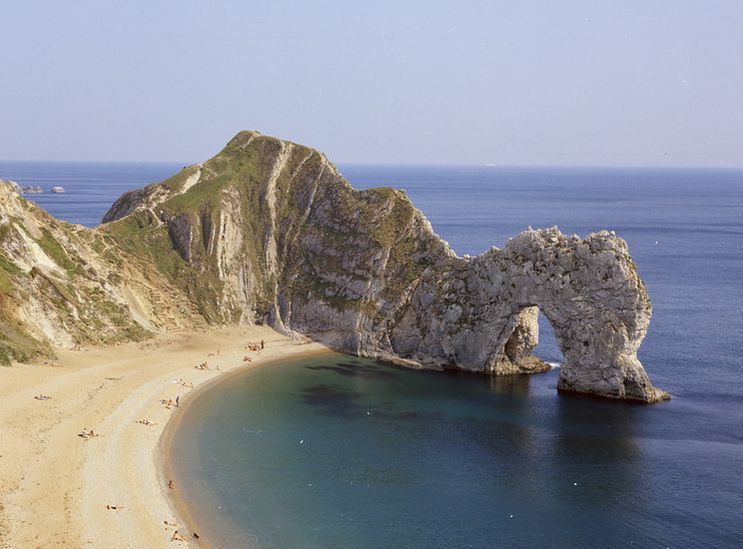 Durdle Door: an arch of rock protruding into the sea by a sandy beach