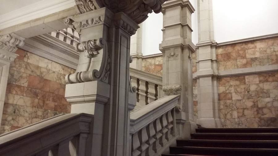An imposing stairase with white marble balustrades, pink alabaster tiles and dark-coloured steps