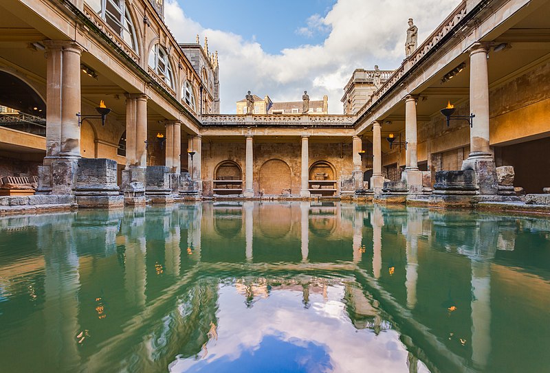 A pool of blue-green water surrounded by a pillared walkway made of yellow rock