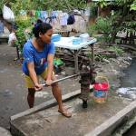 A wom,an pumping water from a public well in a street