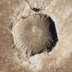 An aerial view of a roughly circular crater in the desert of Arizona