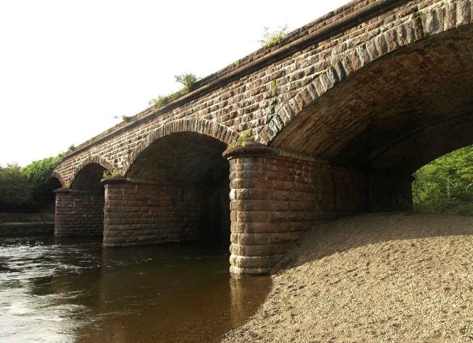 A stone bridge with four arching spanning a river