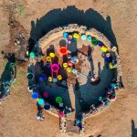 Aerial view of women and children at a borehole in Malawi - source: WaterAid