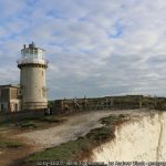 A lighthouse on the edge of a white chalk cliff