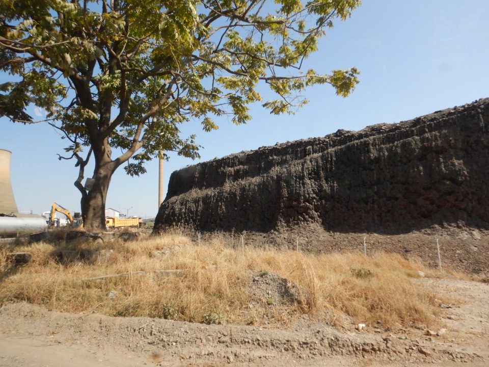 A high, flat-topped pile of black sandy-looking material with steep edges