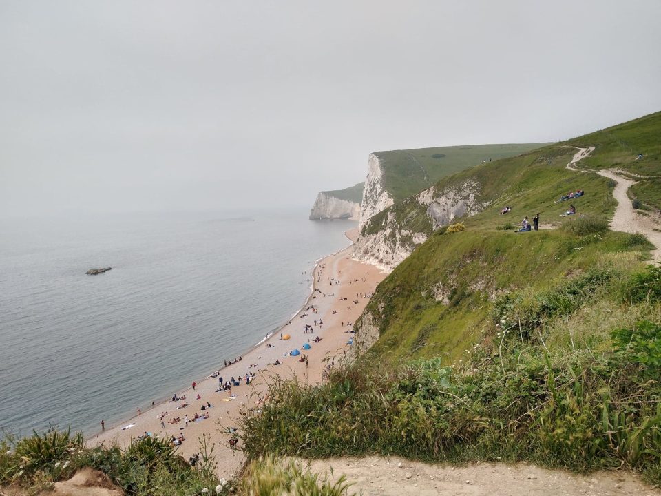 Sandy beaches and white cliffs topped by grassland stretch into the distance