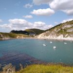 A wide bay with yachts anchored and white cliffs