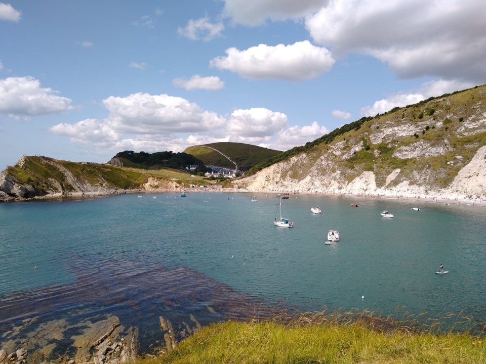 A wide bay with yachts anchored and white cliffs