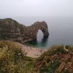 A high rock arch over the sea with a beach at its base