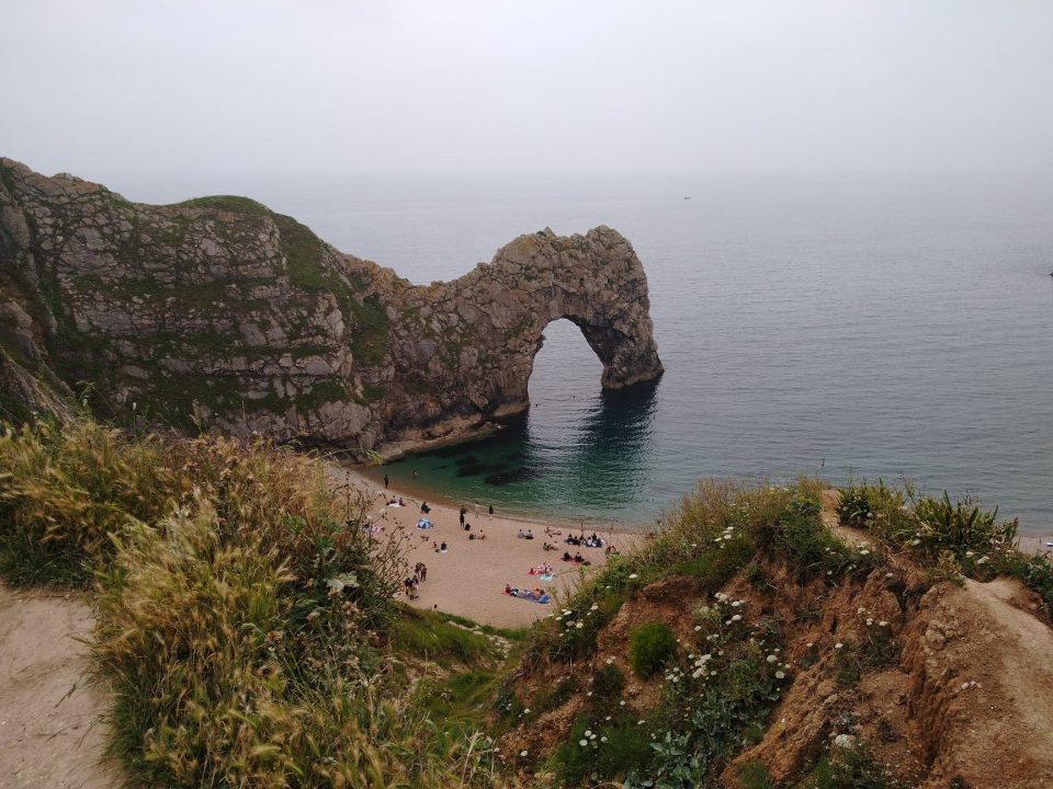 A high rock arch over the sea with a beach at its base