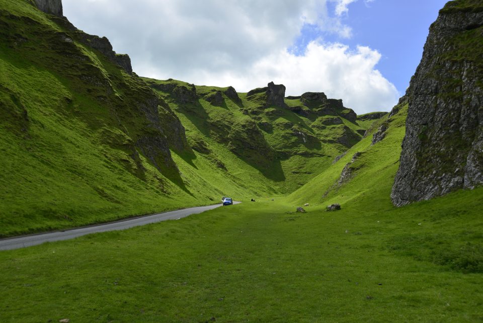 A deep gorge between green hills with a road running down it