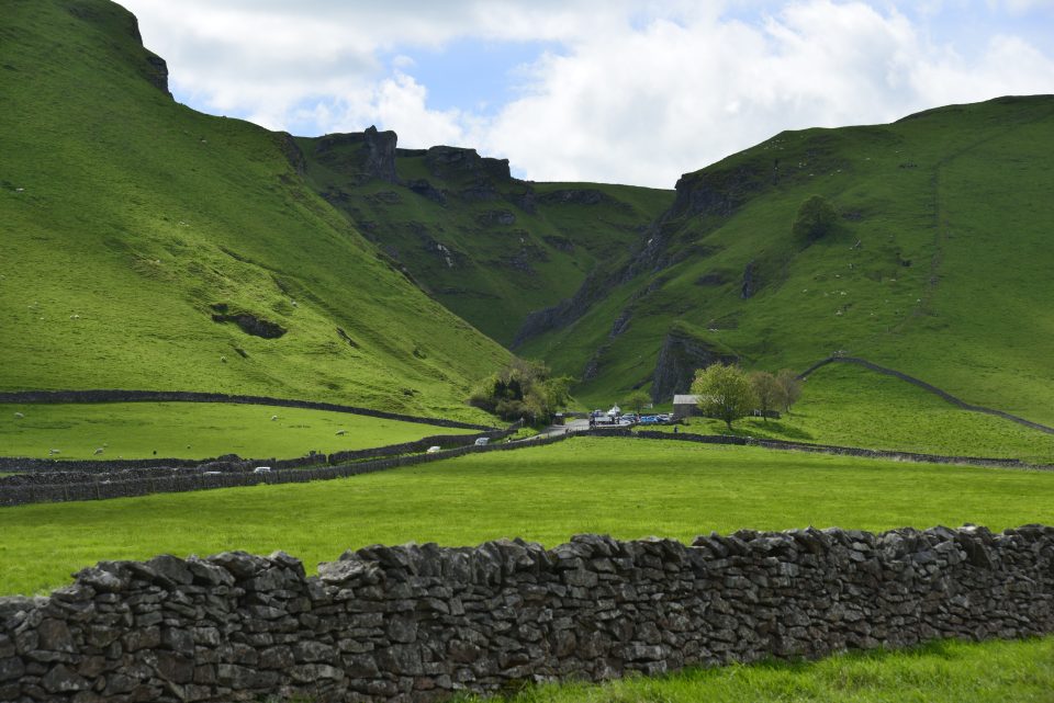 A deep gorge in green hills with rocky outcrops at each side