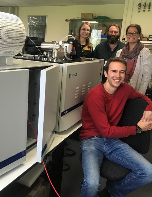 A group of people around lab equipment