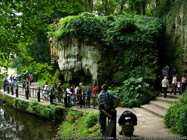 People queuing on a fenced path next to a cave entrance