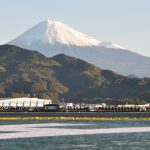 A snow-capped volcano in the background and the oceanside in the foreground