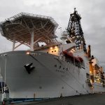 A large white ship moored in a dock, taken from the bow.