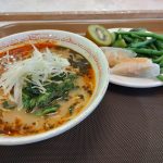 A bowl of soup and a plate of fish steaks and green beans on a table