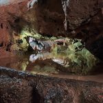 a still pool of water perfectly reflecting the cave walls around it