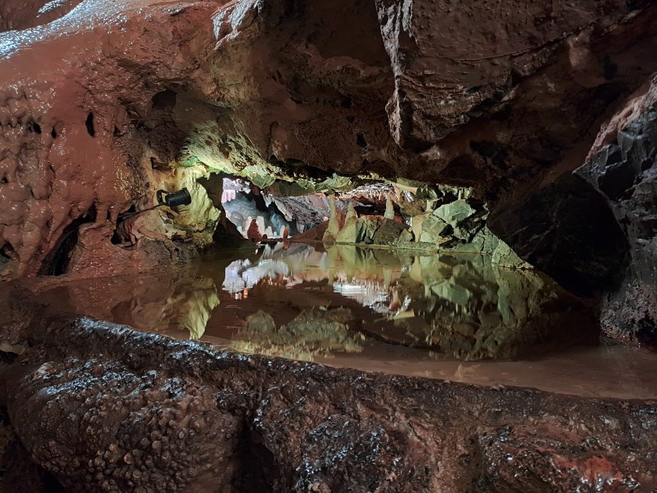 a still pool of water perfectly reflecting the cave walls around it