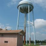 A spherical pale blue water tower next to a brick building