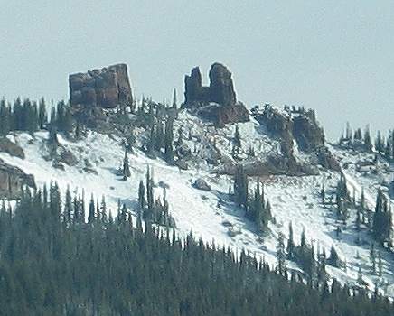 Two rock formations on top of a snowy hill. The one on the left is a square block; the one on the right resembles a pair of rabbit's ears