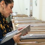 A woman carrying a notebook examines a piece of rock core