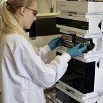 A woman in a white lab coat uses a piece of laboratory equipment