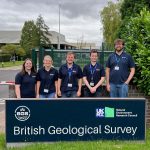 Five students stand behind a sign for the British Geological Survey