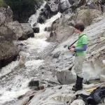 Observing the sparsely fractured (unfaulted) wacke sandstone in the bed of the Gameshope Burn. BGS © UKRI.