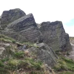 The ash from the volcanoes in the area would have settled under water to create layered deposits. This outcrop is on the same hill as Old John Tower. BGS © UKRI.