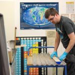 A man places a piece of core into a plastic tray