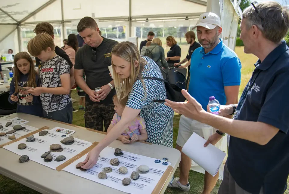 A BGS geologist explains the rock samples on display to a family.