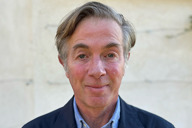 A white man with brown hair and eyes smiling at the camera