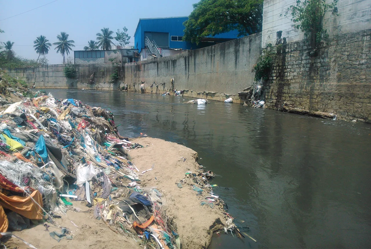 Waste next to a river with buildings in the background.