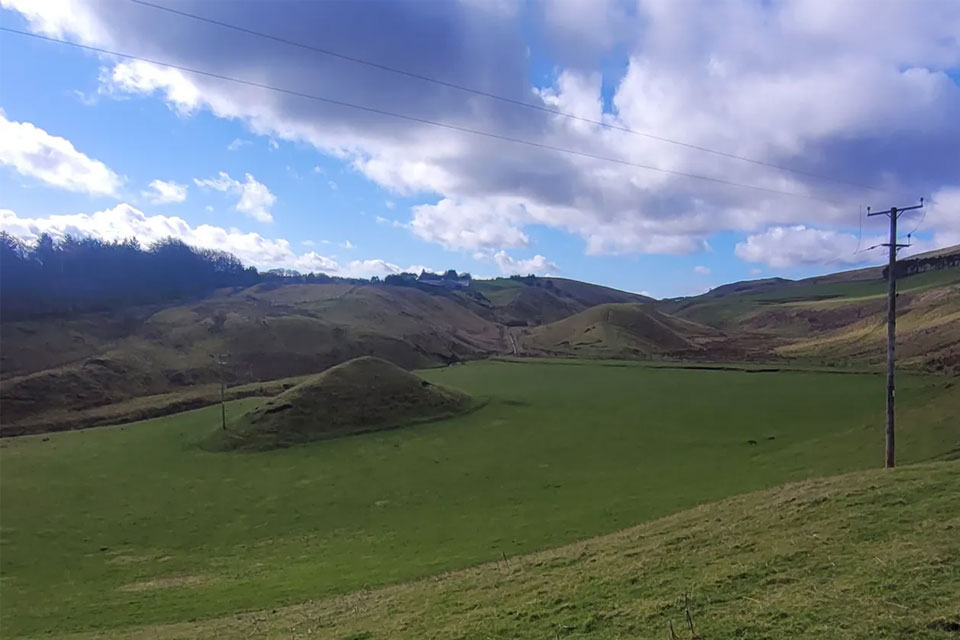 Valley and rock islands at Carlops. The telephone poles help emphasise the scale of the valley and serve as a useful analogue for the general spacing of ground-truth sites offshore, which often miss the variability of geological conditions. Offshore valleys formed by meltwater can be up to ten times larger than the one shown here, reaching several hundreds of metres in depth. BGS © UKRI.